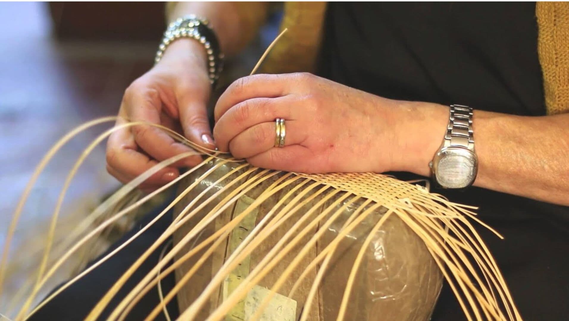 Artisan weaving rattan strips into a bag
