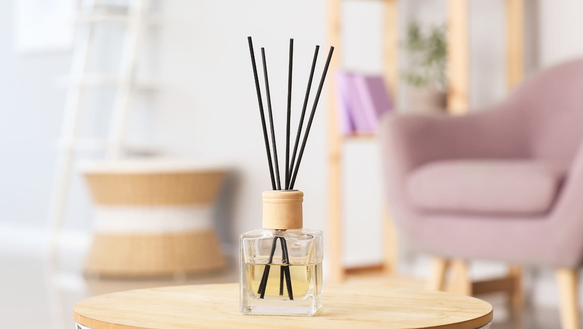 Rattan reeds in a glass diffuser on a wooden table