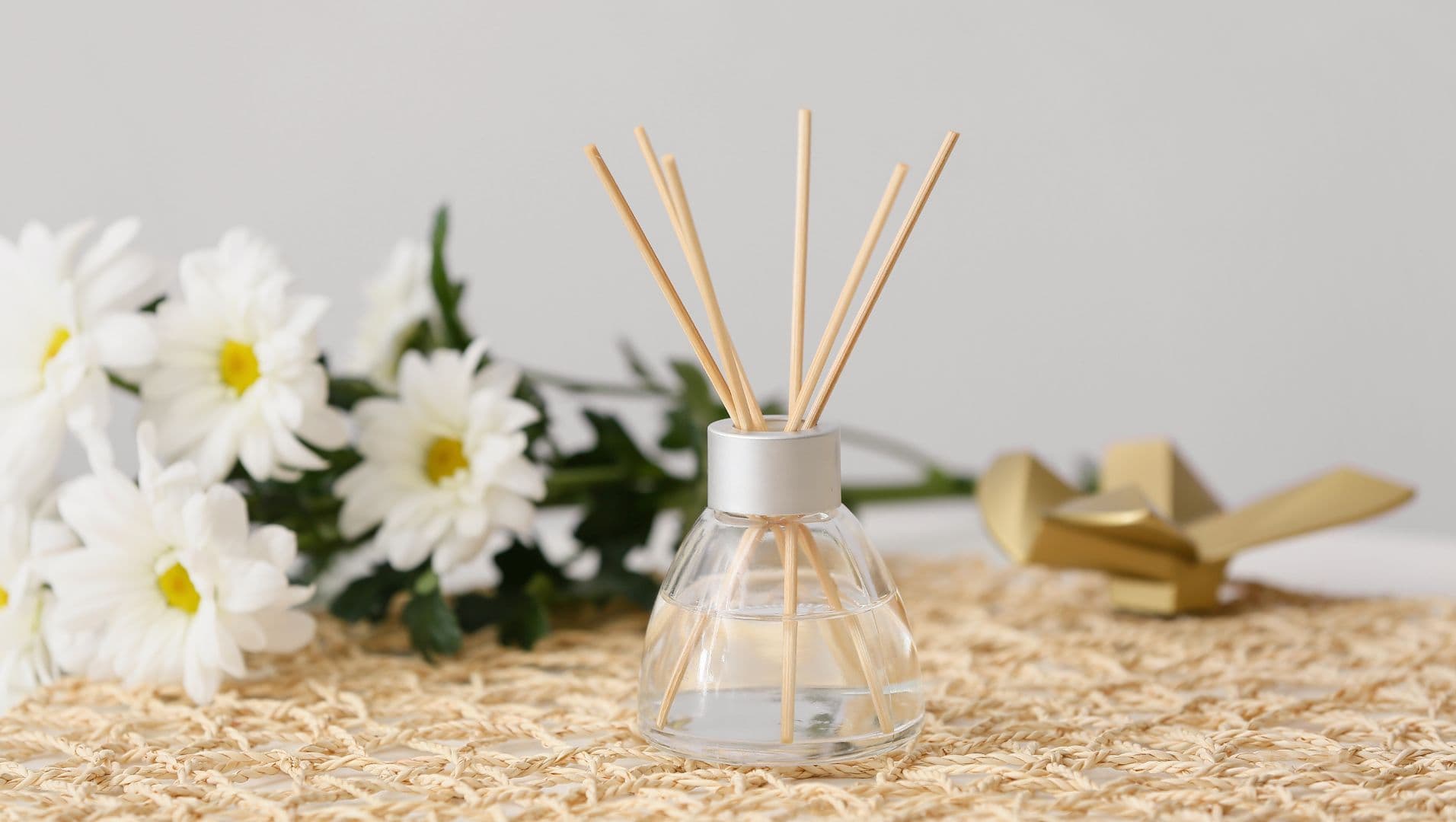Reed diffuser with essential oil bottles and flowers on a wooden table